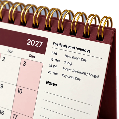 2027 desk calendar in Maroon, close-up of the gold wire-o binding, punched holes and festival list